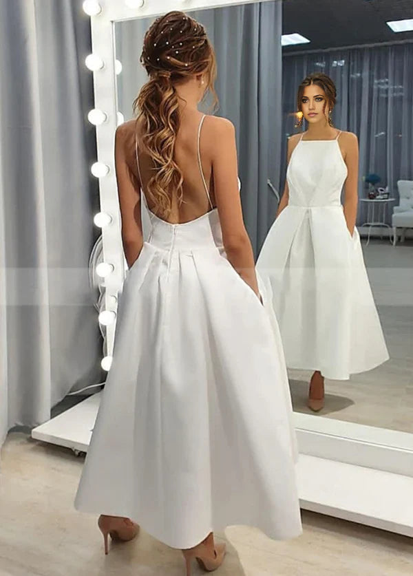 Vestido de novia sencillo de corte A, sin mangas, con tirantes finos, espalda abierta, largo hasta la rodilla y bolsillos